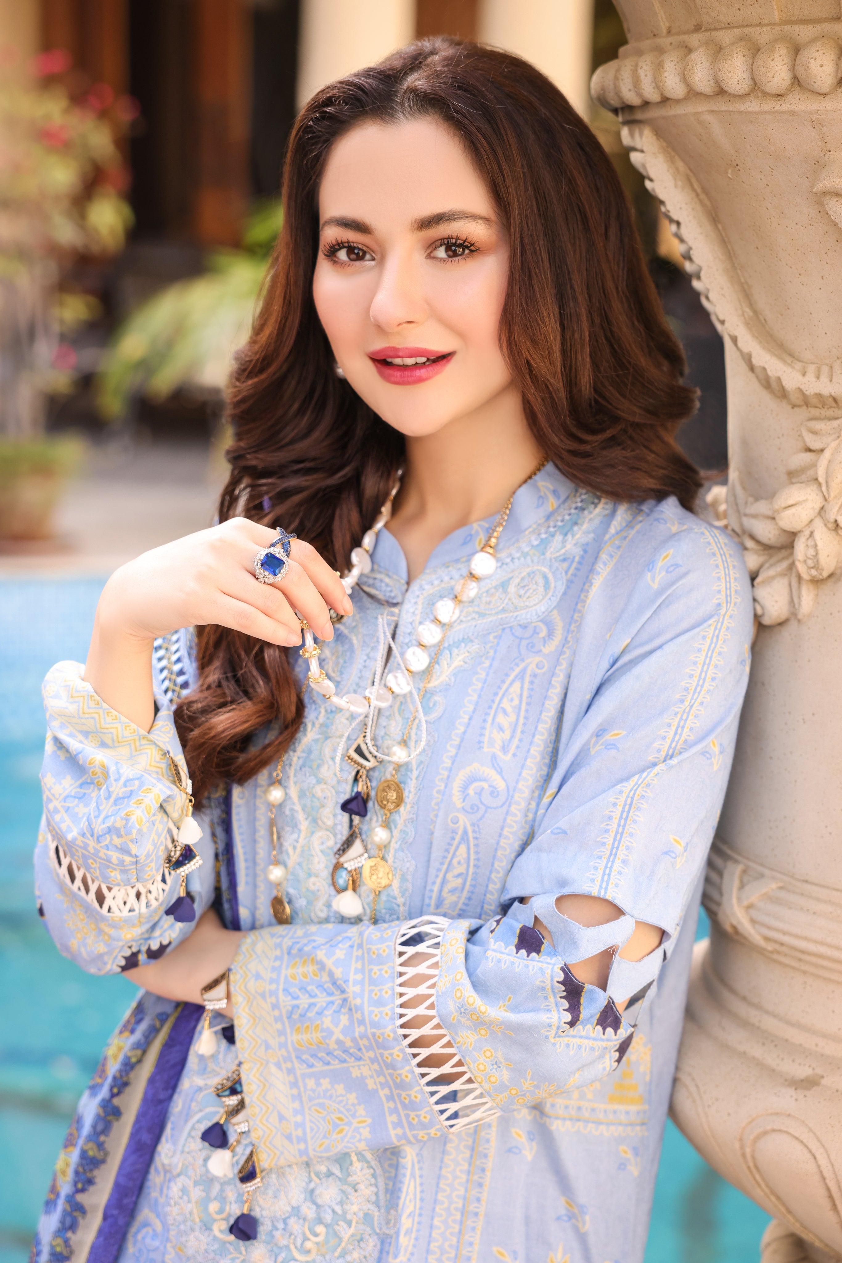 A girl is posing for picture holding her nacklace in blue Embroidered Organza Suit.