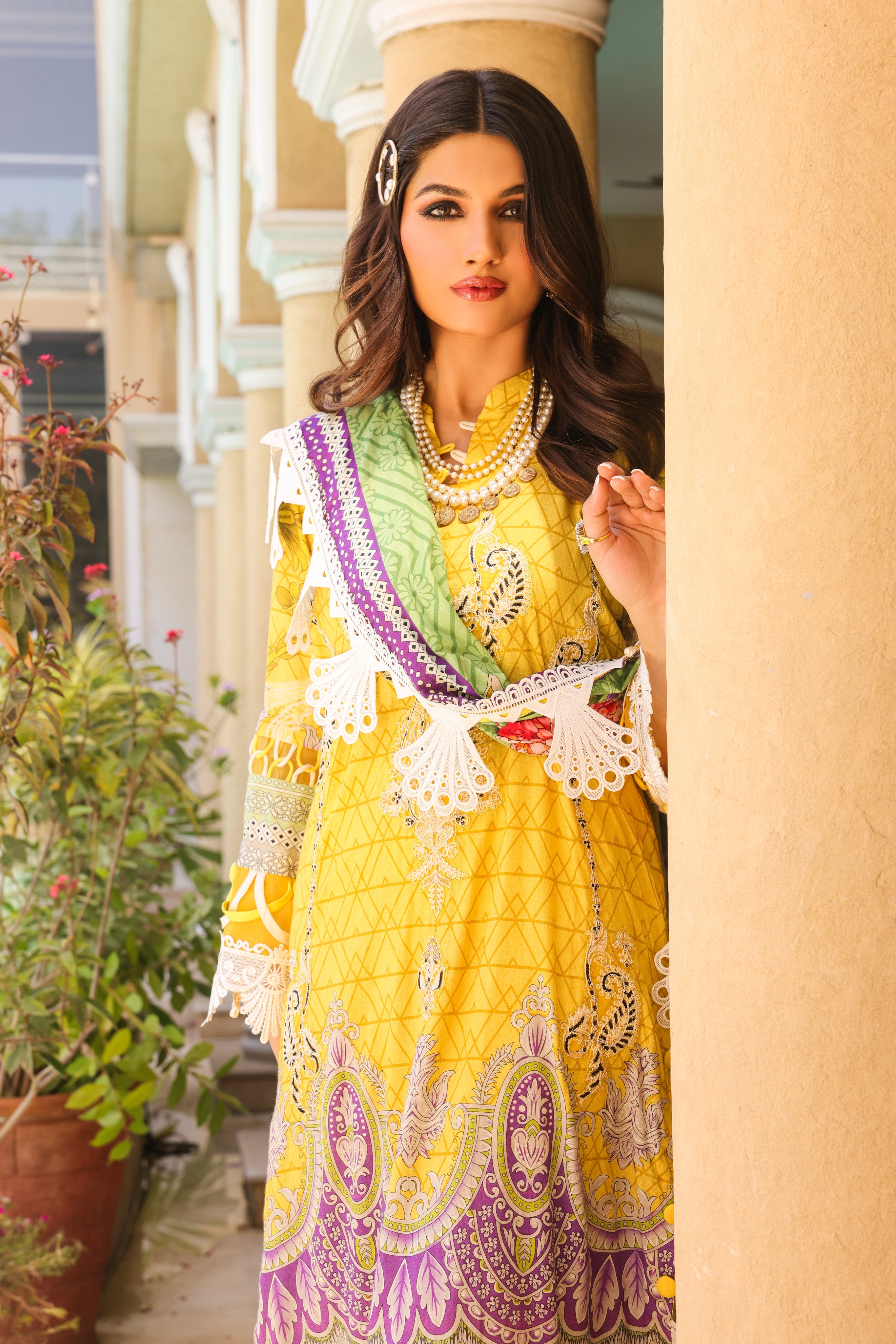 A girl is standing beside the pillar in the 3 Piece Embroidered Organza Suit of Illuminating Yellow color.