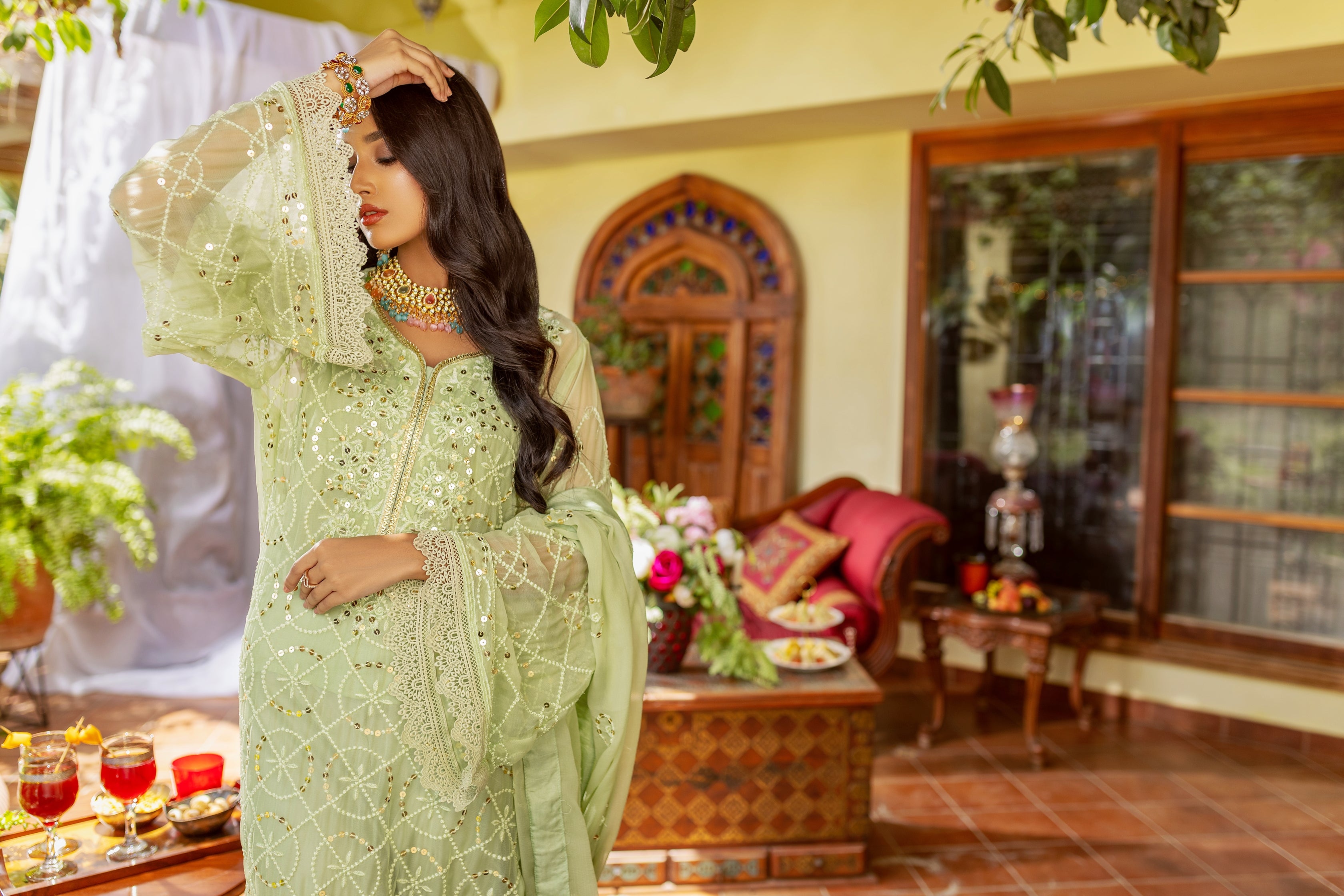 A female model in Light green chiffon embroided suit showing the selves design.