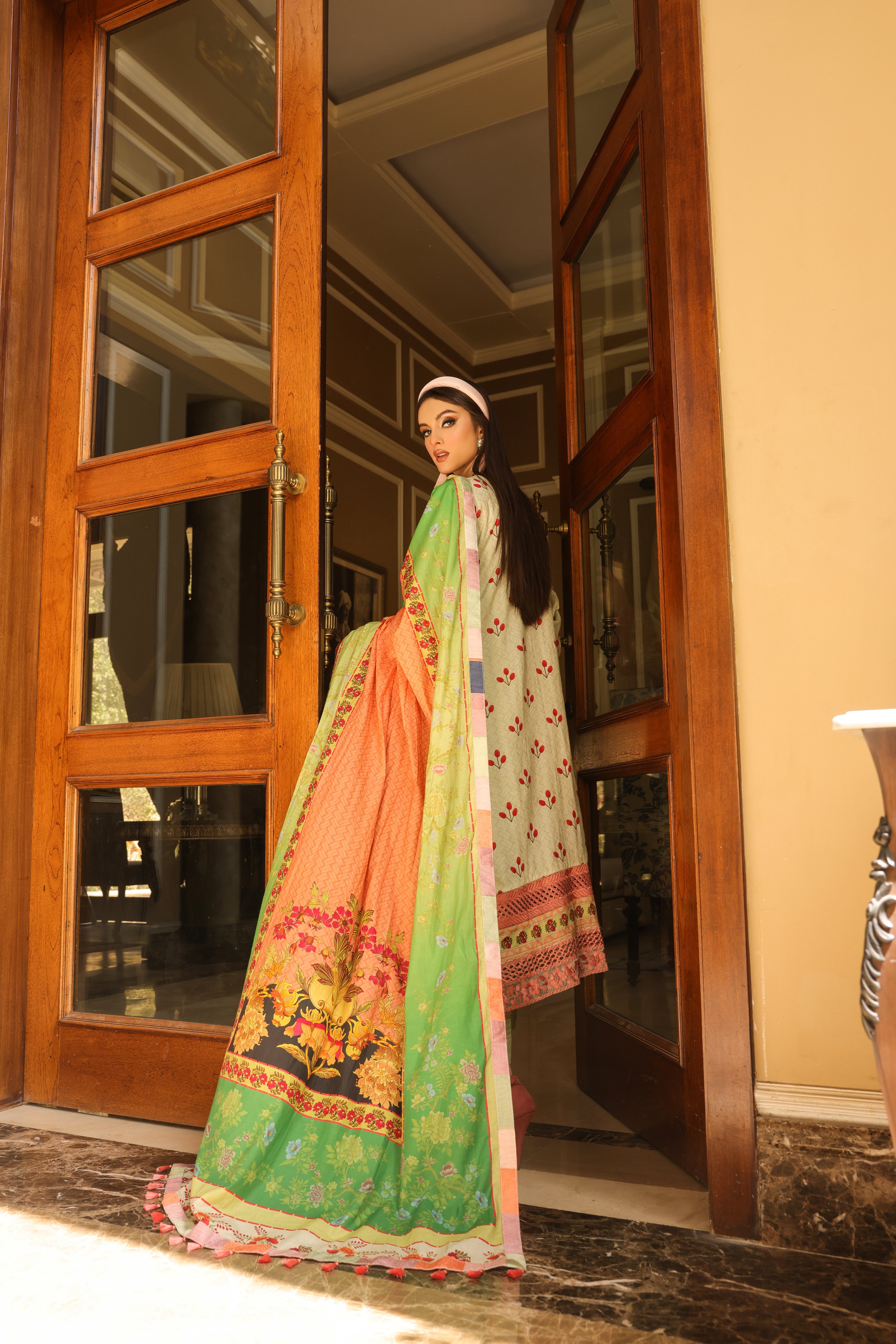 A girl is standing in a door way wearing a Embroidered Organza Suit of Lime colour with dupatta.